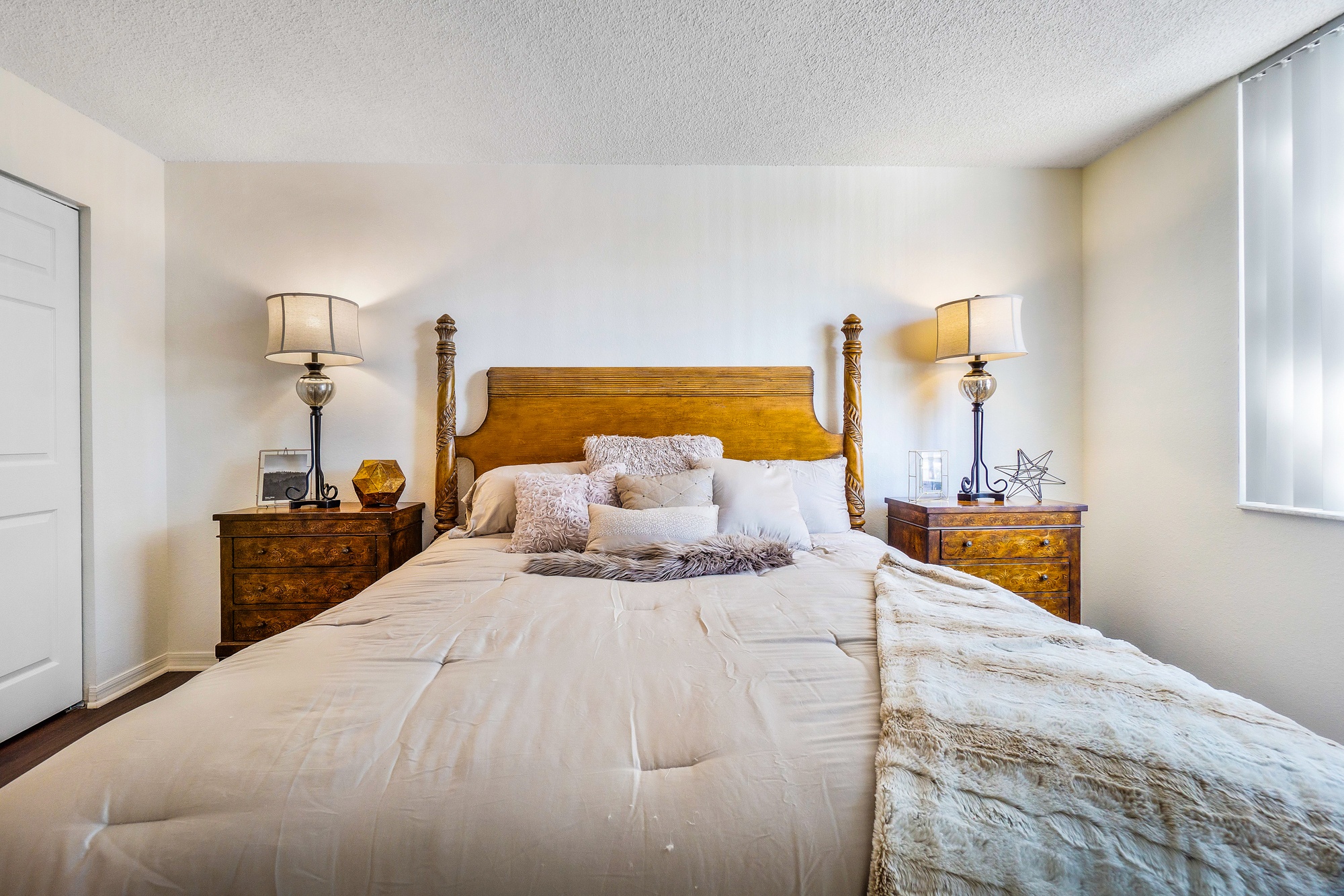 A bedroom with a large bed and two lamps on either side.